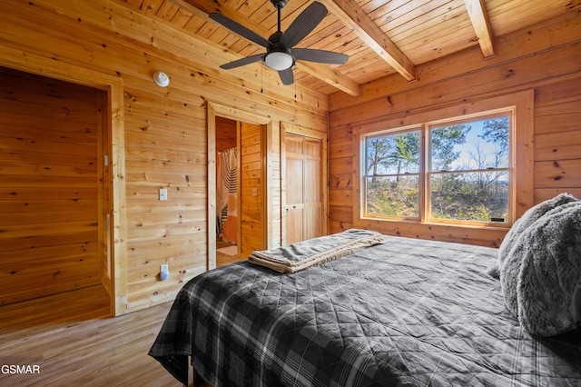 bedroom with wood ceiling, wood-type flooring, wooden walls, ceiling fan, and beam ceiling