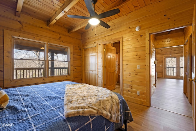 bedroom with ceiling fan, wood walls, wood-type flooring, beamed ceiling, and wooden ceiling