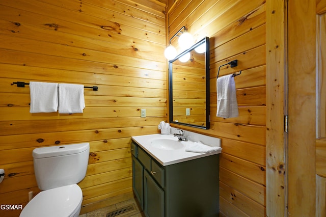 bathroom featuring toilet, vanity, and wooden walls