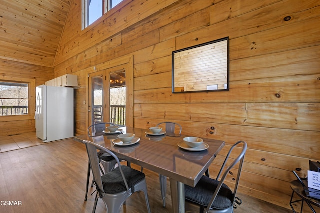 dining space with high vaulted ceiling, plenty of natural light, and light hardwood / wood-style floors