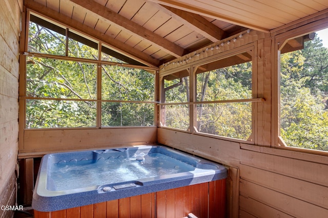 unfurnished sunroom with lofted ceiling with beams, plenty of natural light, wooden ceiling, and a hot tub