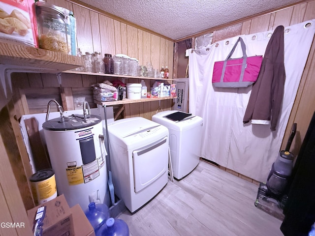 clothes washing area featuring electric water heater, a textured ceiling, separate washer and dryer, light wood-type flooring, and wood walls