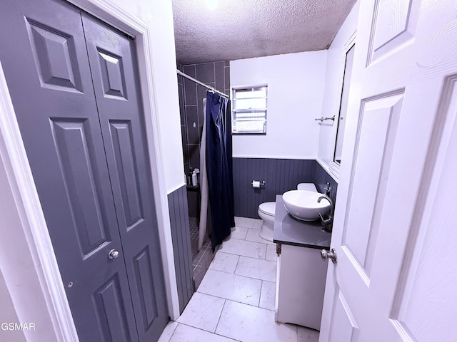 bathroom featuring vanity, toilet, a textured ceiling, and walk in shower