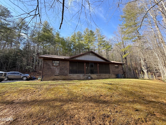 view of front facade with central AC unit, a sunroom, and a front yard