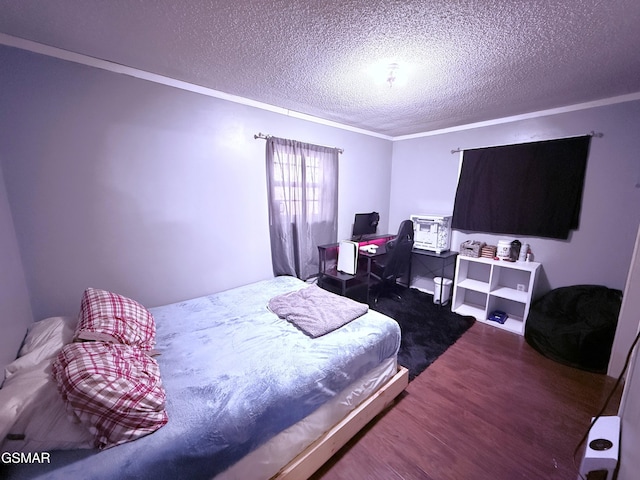 bedroom featuring wood-type flooring, ornamental molding, and a textured ceiling