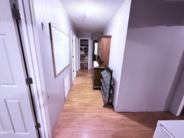 corridor with crown molding, a textured ceiling, and light hardwood / wood-style flooring