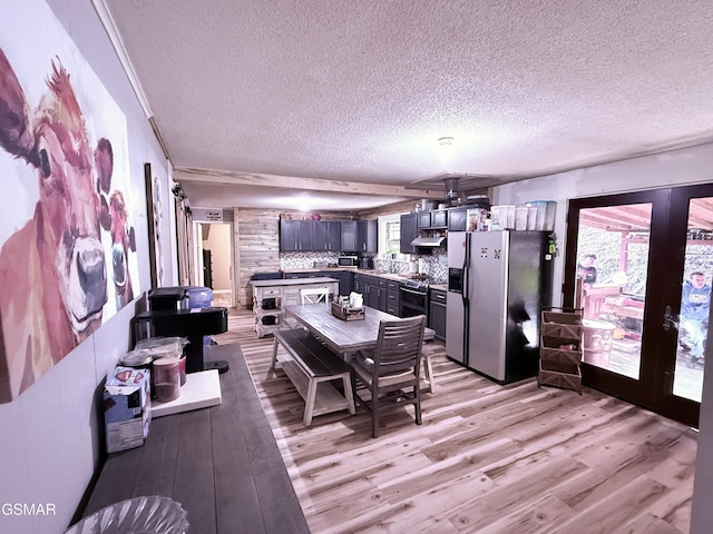 dining space with a textured ceiling, light hardwood / wood-style floors, and french doors