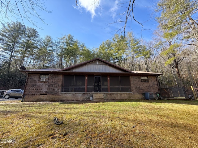 view of front of house with a sunroom, a front yard, and central air condition unit