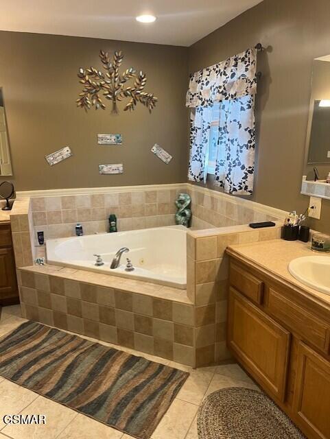 bathroom with tile patterned floors, vanity, and a relaxing tiled tub