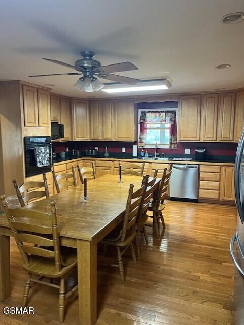 kitchen with light brown cabinets, black appliances, sink, ceiling fan, and light wood-type flooring