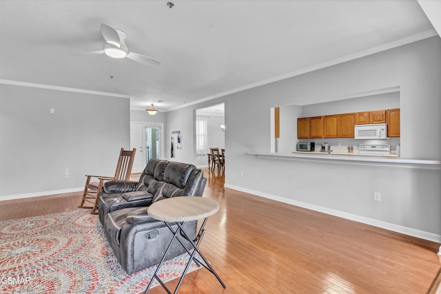 living room featuring ceiling fan, ornamental molding, and light hardwood / wood-style flooring