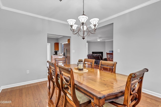 dining area with crown molding, a notable chandelier, and light hardwood / wood-style flooring