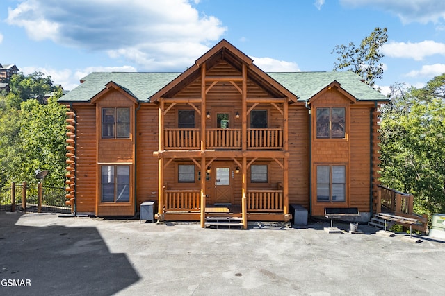 log home featuring log siding, a balcony, and a shingled roof