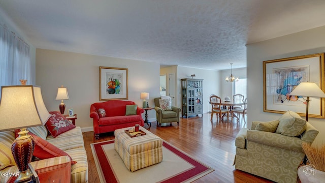 living room featuring a notable chandelier, hardwood / wood-style flooring, and a textured ceiling