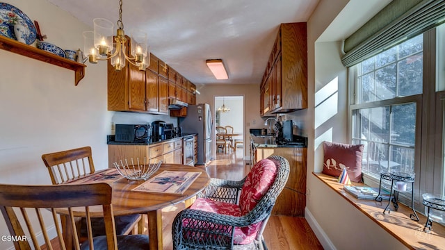 kitchen featuring hanging light fixtures, stainless steel fridge, a chandelier, and light hardwood / wood-style flooring