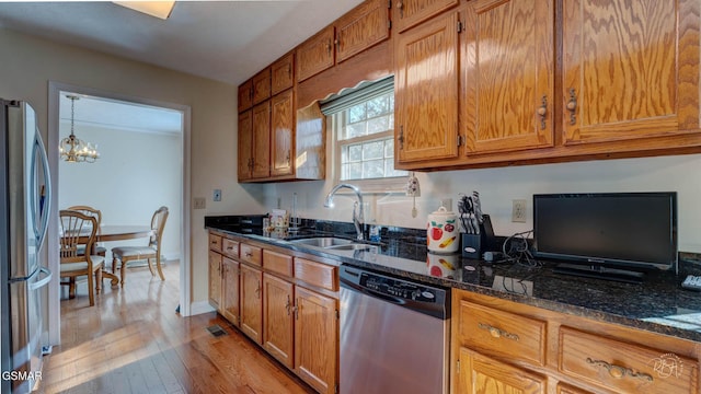 kitchen featuring sink, light hardwood / wood-style flooring, dark stone counters, pendant lighting, and stainless steel appliances