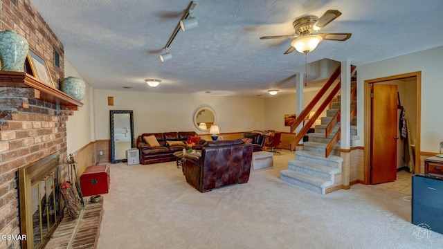 living room featuring carpet flooring, track lighting, a fireplace, and a textured ceiling