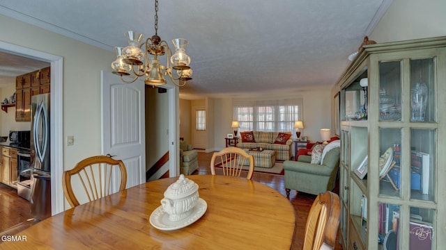 dining room with crown molding, hardwood / wood-style floors, a textured ceiling, and a chandelier