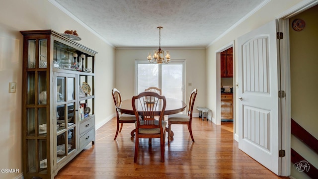 dining area featuring crown molding, hardwood / wood-style flooring, a textured ceiling, and a chandelier