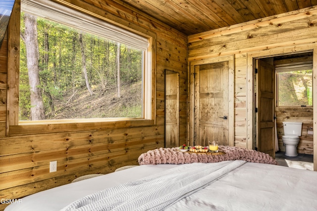 bedroom featuring wooden ceiling, ensuite bath, and wooden walls