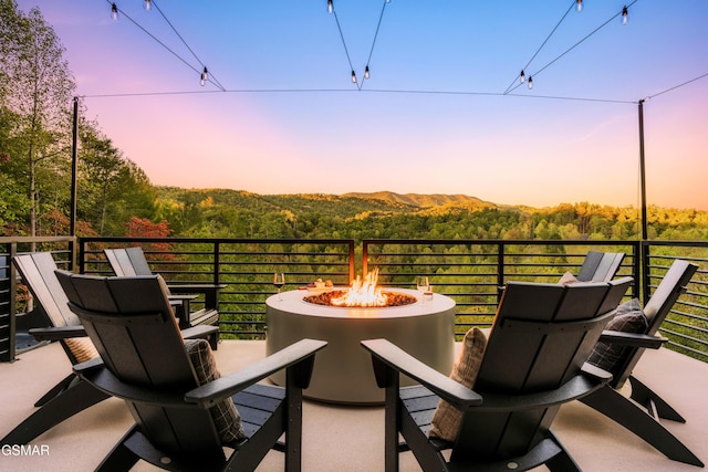 balcony at dusk featuring an outdoor fire pit