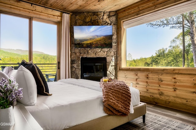 bedroom featuring a fireplace, wood finished floors, wood ceiling, and wooden walls