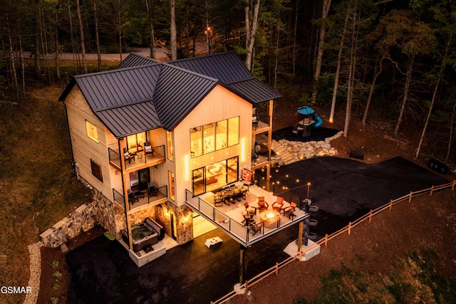 back of house with a patio, a standing seam roof, fence, a balcony, and metal roof