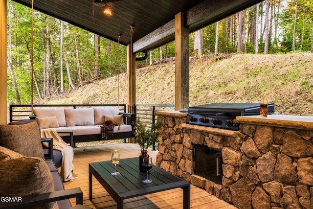 view of patio with a deck, a grill, an outdoor living space, and a forest view