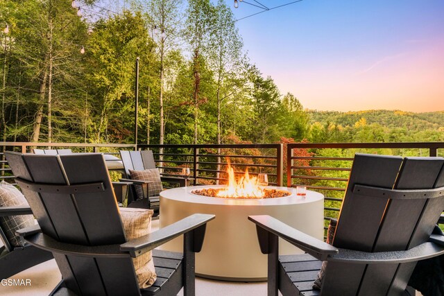 patio terrace at dusk with a mountain view, a balcony, and a fire pit