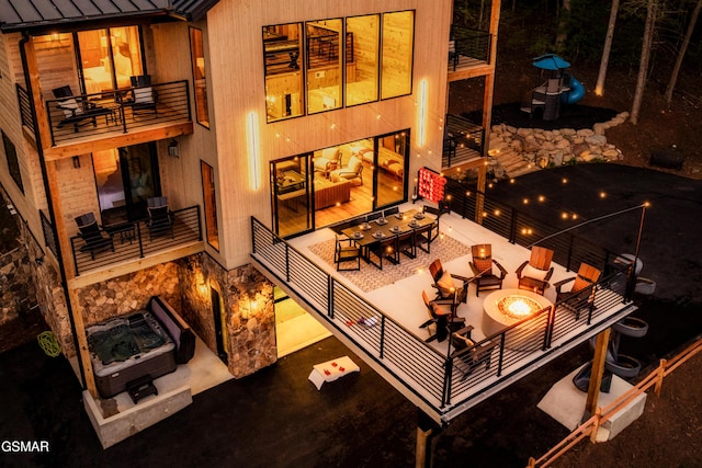 interior space with an outdoor fire pit, a hot tub, and a balcony