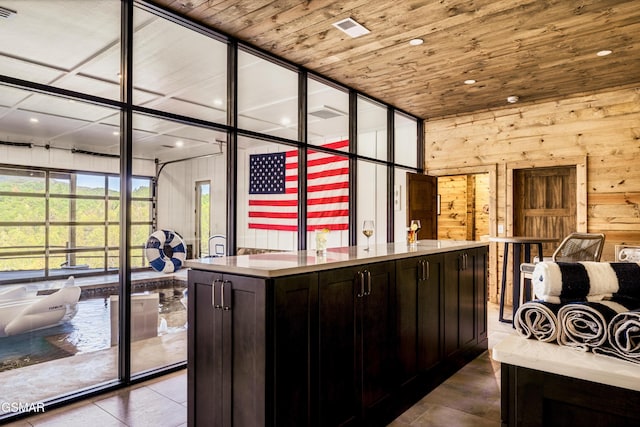 bar with dark brown cabinetry, wooden walls, and wooden ceiling