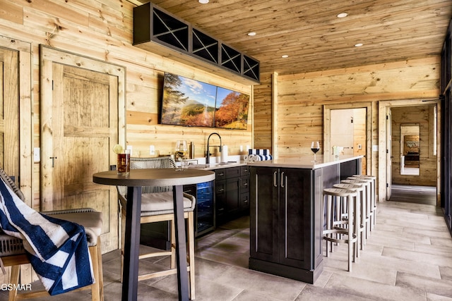 bar featuring wood walls, wooden ceiling, a sink, and recessed lighting