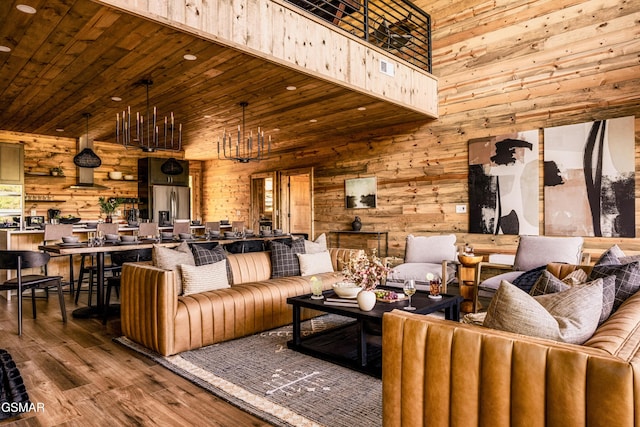 living room featuring wooden ceiling, a high ceiling, wood walls, wood finished floors, and an inviting chandelier