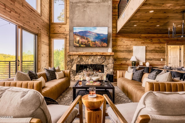 living area with a stone fireplace, a healthy amount of sunlight, a towering ceiling, and wooden walls