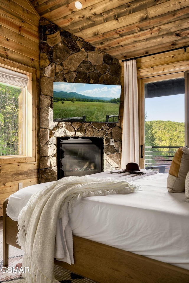 bedroom with access to outside, wood ceiling, vaulted ceiling, and a stone fireplace