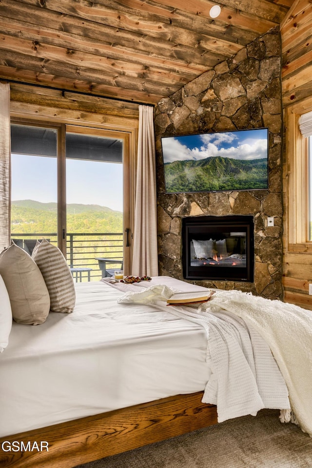 bedroom with access to outside, wood ceiling, vaulted ceiling, and a stone fireplace