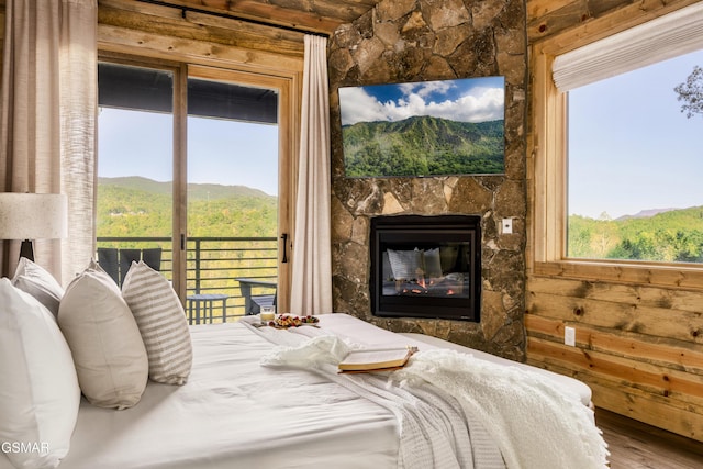 bedroom featuring access to exterior, a mountain view, a fireplace, and hardwood / wood-style floors