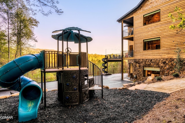 playground at dusk featuring a playground and a patio