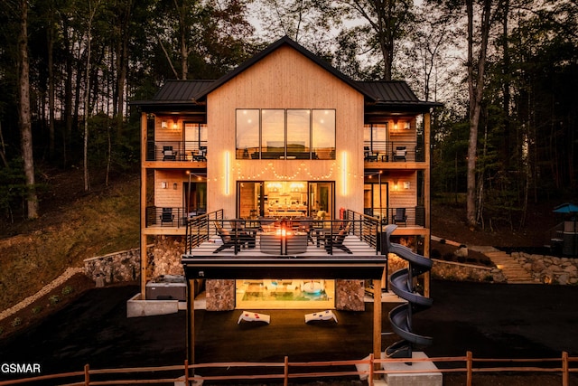 rear view of property featuring a standing seam roof, fence, a balcony, and metal roof