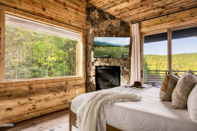 bedroom featuring a fireplace, multiple windows, lofted ceiling, and wood ceiling