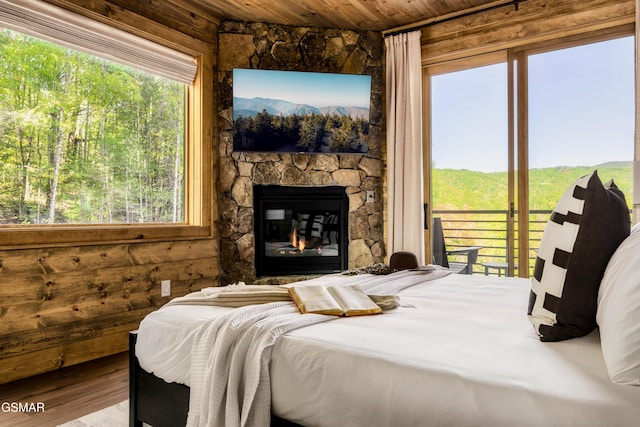 bedroom featuring access to outside, wood ceiling, a fireplace, and wood finished floors