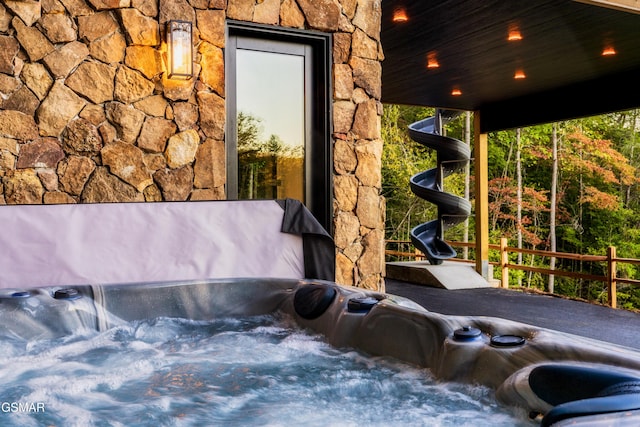 exterior space with stone siding and a hot tub