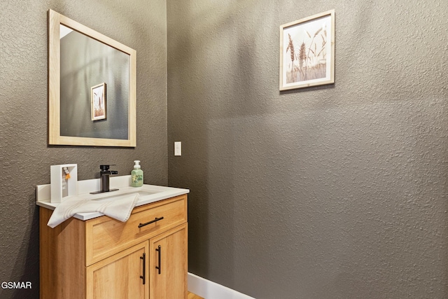 bathroom with a textured wall and vanity