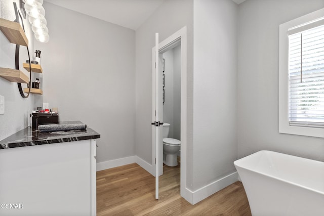 bathroom with a freestanding bath, wood finished floors, vanity, and baseboards