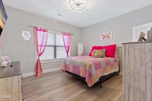 bedroom with light wood-type flooring, visible vents, and baseboards