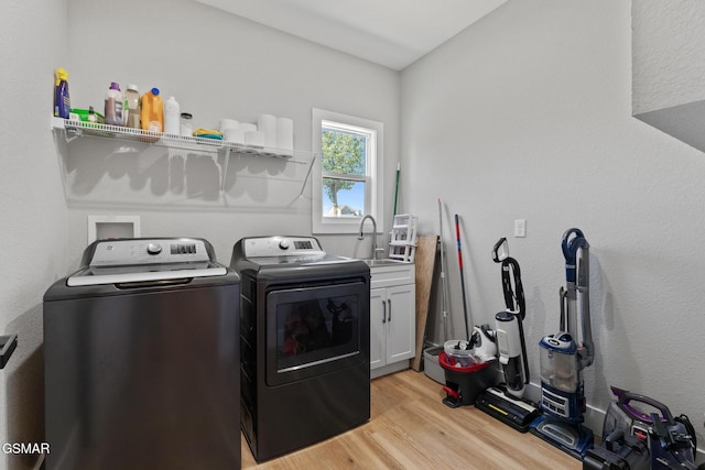 laundry room with separate washer and dryer, light wood-style flooring, a sink, and cabinet space