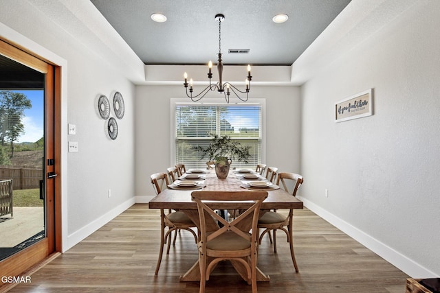 dining space with light wood finished floors, baseboards, visible vents, and an inviting chandelier