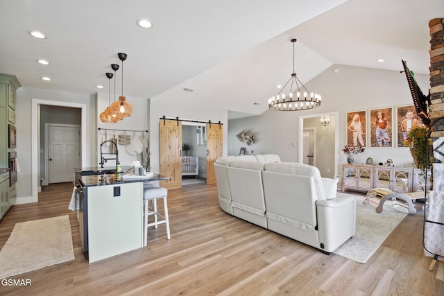 living room featuring a barn door, vaulted ceiling, light wood-style flooring, and recessed lighting