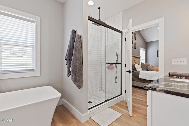 ensuite bathroom with wood finished floors, a freestanding tub, a shower stall, and connected bathroom