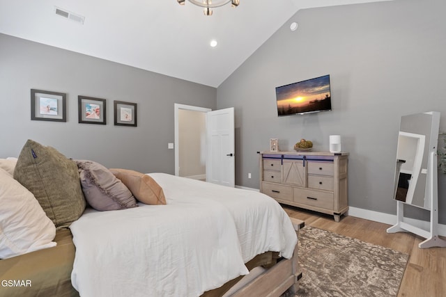 bedroom with high vaulted ceiling, light wood finished floors, visible vents, and baseboards